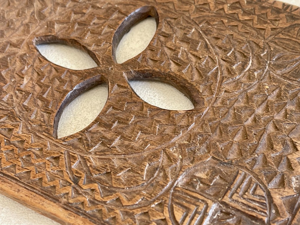 A rectangular antique wooden treen lace folder decorated with intricate geometric chip carving, circular roundels, and a central four-petal pierced motif. View II