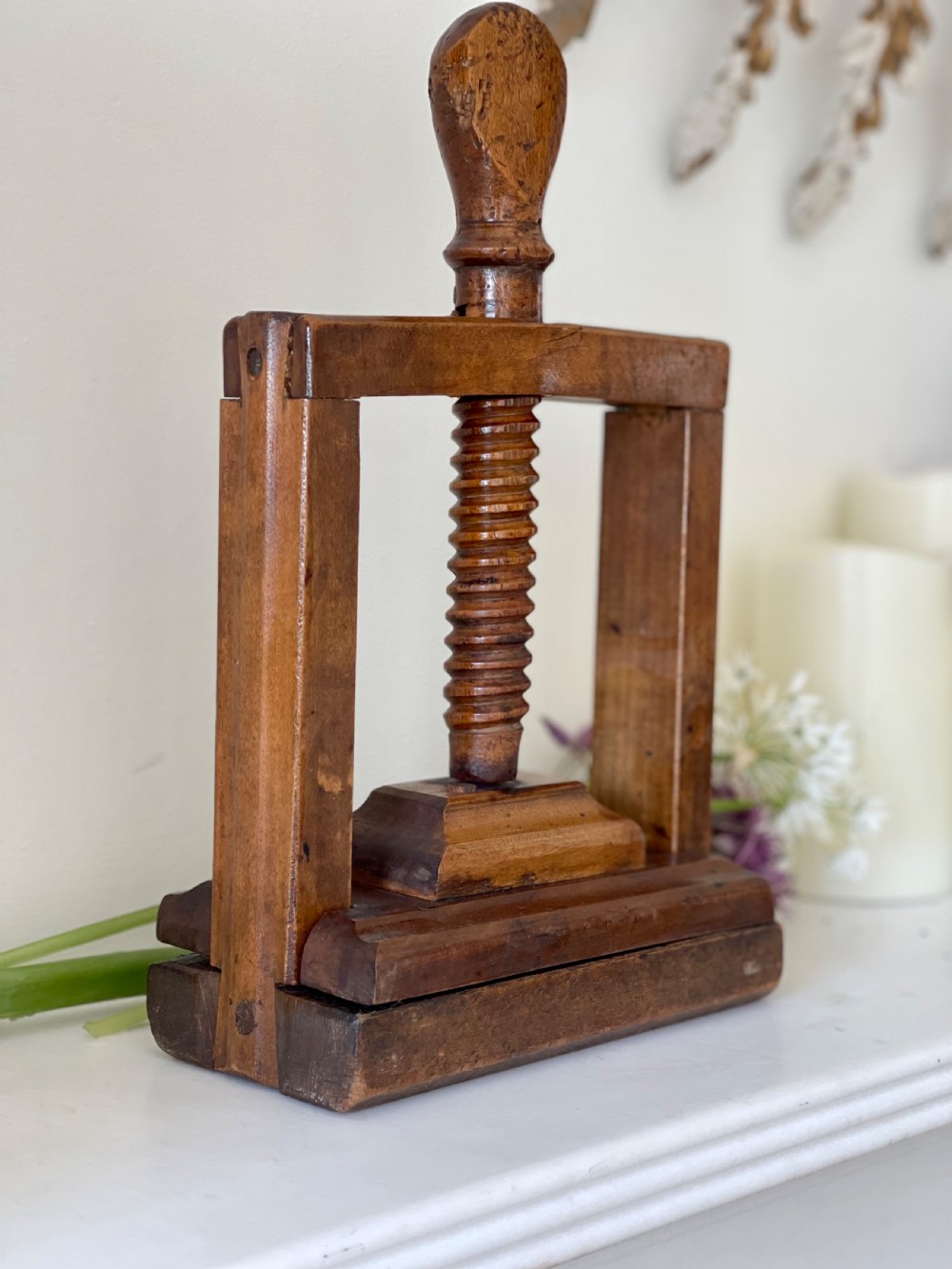 A small antique wooden book and flower press featuring a central threaded screw mechanism and dark brown patina.