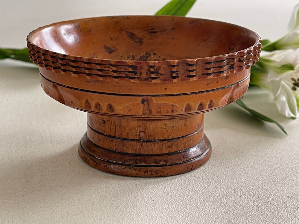 A small turned warm brown wooden Georgian searce with a carved wavy rim, pedestal base, and perforated strainer bottom. View II