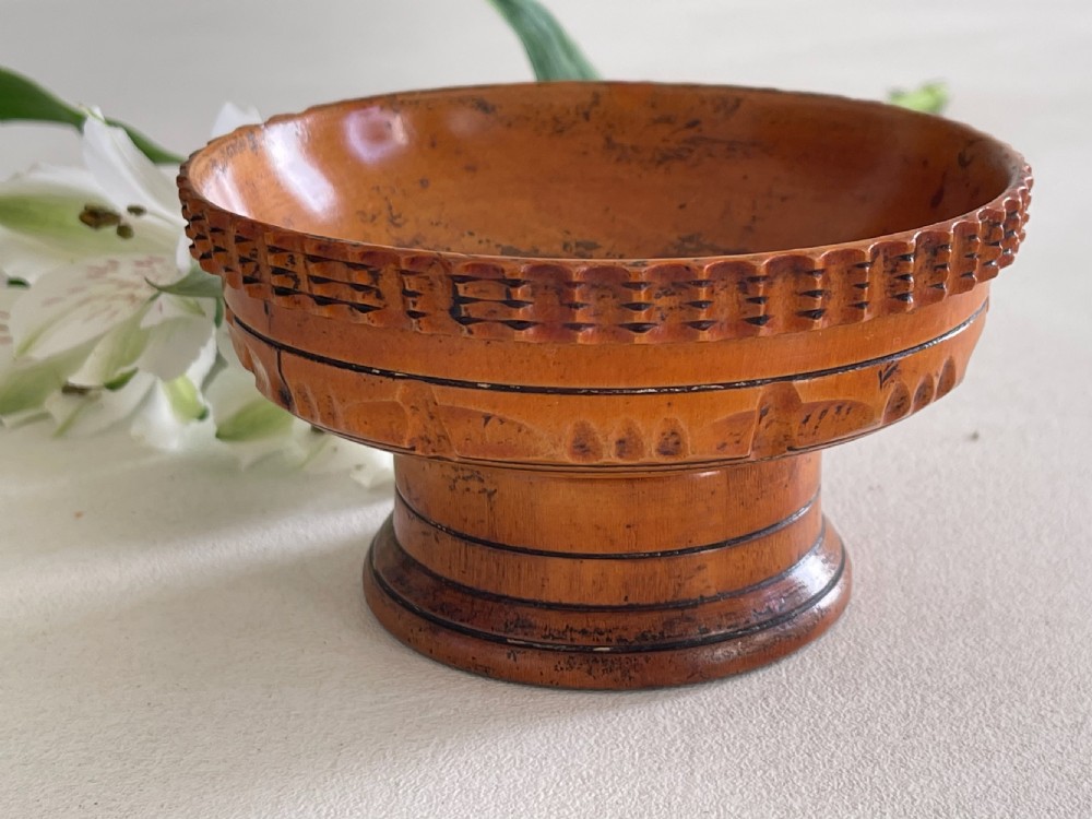 A small turned warm brown wooden Georgian searce with a carved wavy rim, pedestal base, and perforated strainer bottom. View IV
