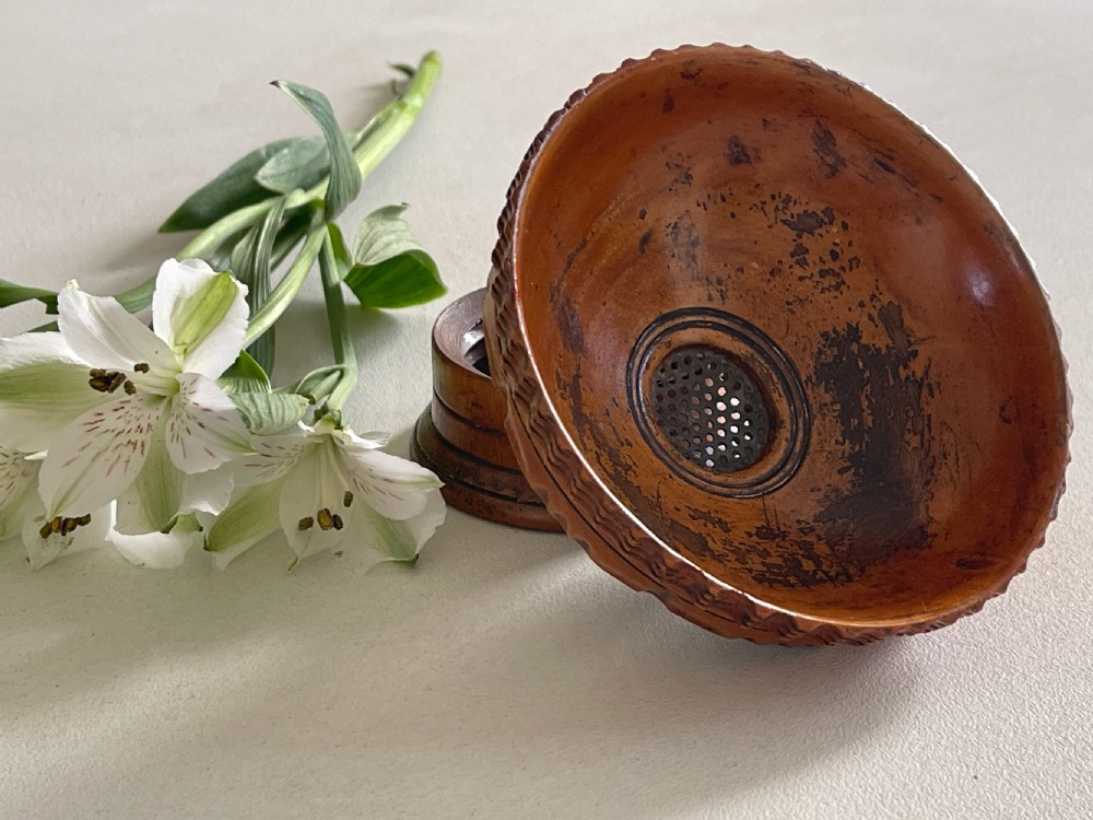 A small turned warm brown wooden Georgian searce with a carved wavy rim, pedestal base, and perforated strainer bottom. View VI