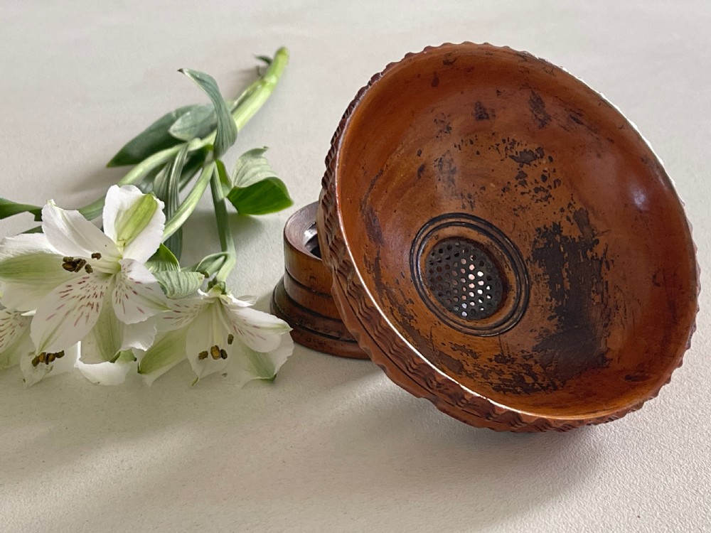 A small turned warm brown wooden Georgian searce with a carved wavy rim, pedestal base, and perforated strainer bottom. View VII