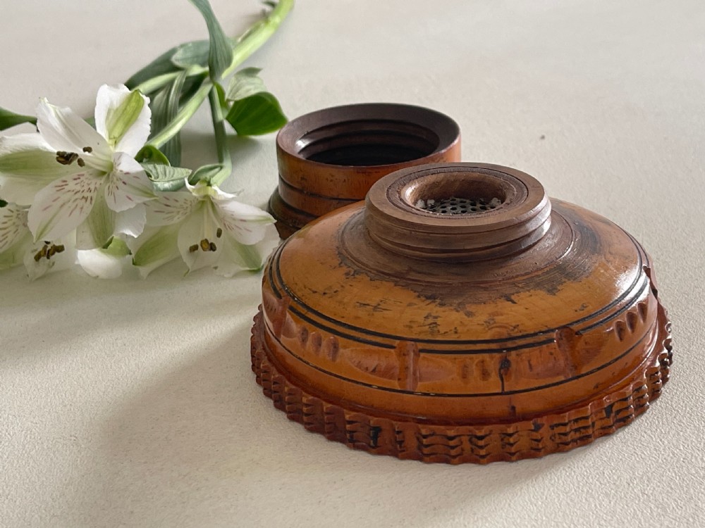 A small turned warm brown wooden Georgian searce with a carved wavy rim, pedestal base, and perforated strainer bottom. View IX