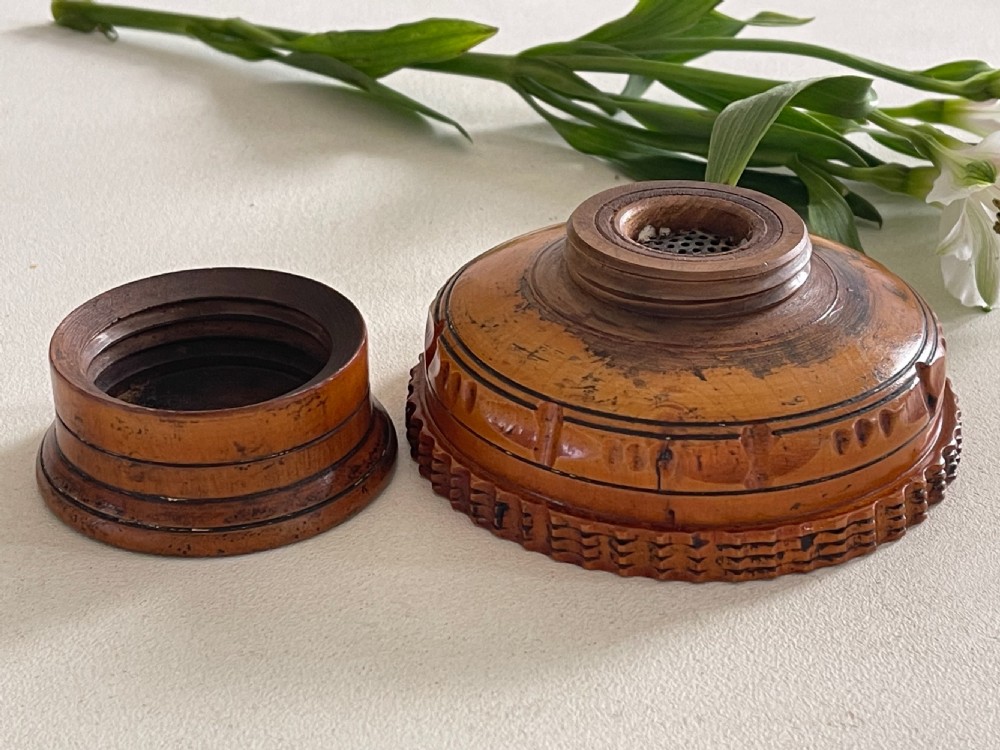 A small turned warm brown wooden Georgian searce with a carved wavy rim, pedestal base, and perforated strainer bottom. View XI
