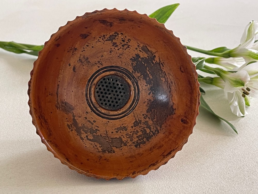 A small turned warm brown wooden Georgian searce with a carved wavy rim, pedestal base, and perforated strainer bottom. View XV