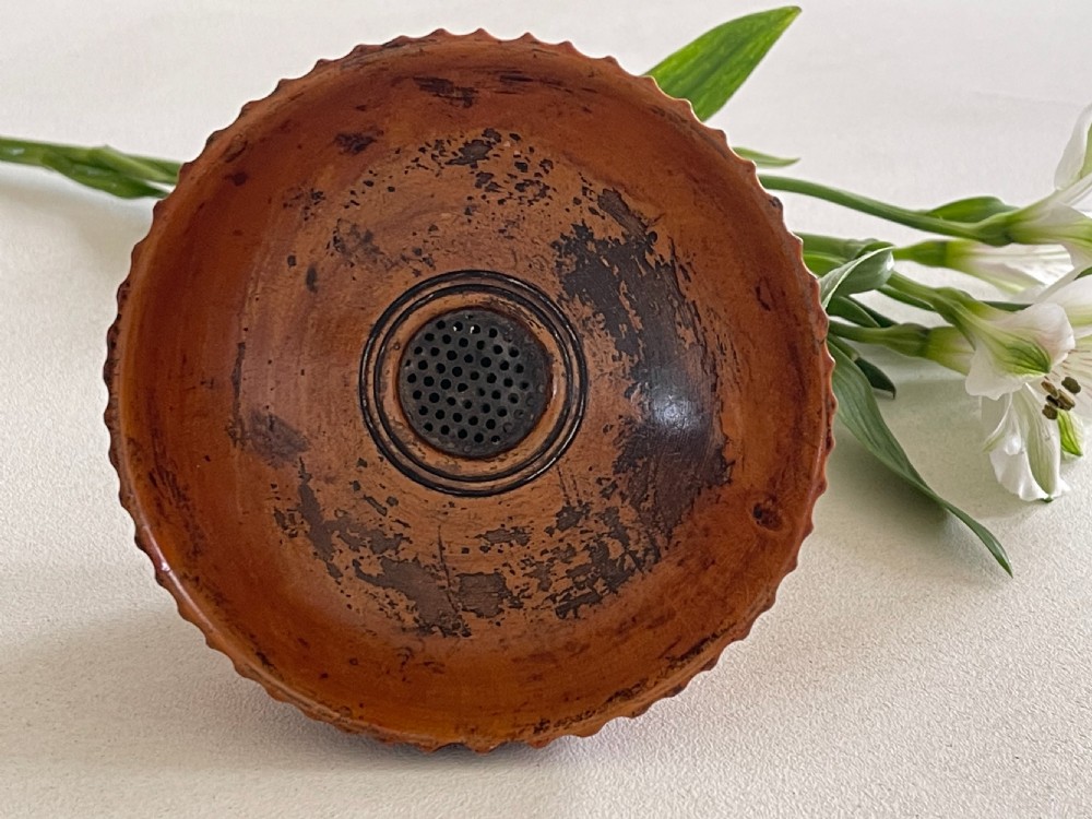 A small turned warm brown wooden Georgian searce with a carved wavy rim, pedestal base, and perforated strainer bottom. View XVI
