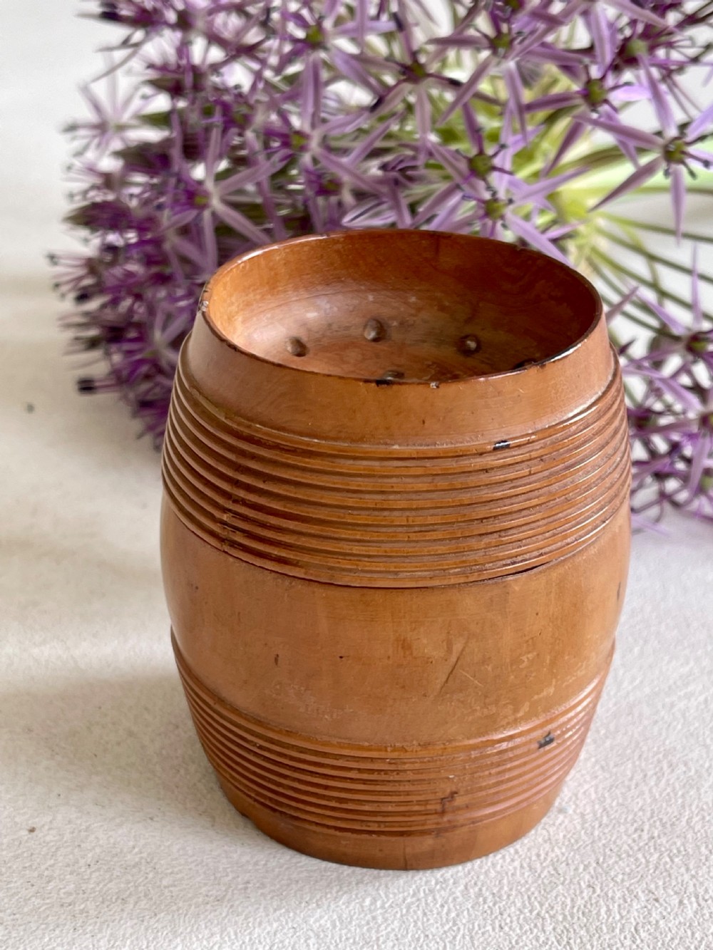 A small turned wooden pounce pot displaying a reeded base and a perforated concave top lid. View II