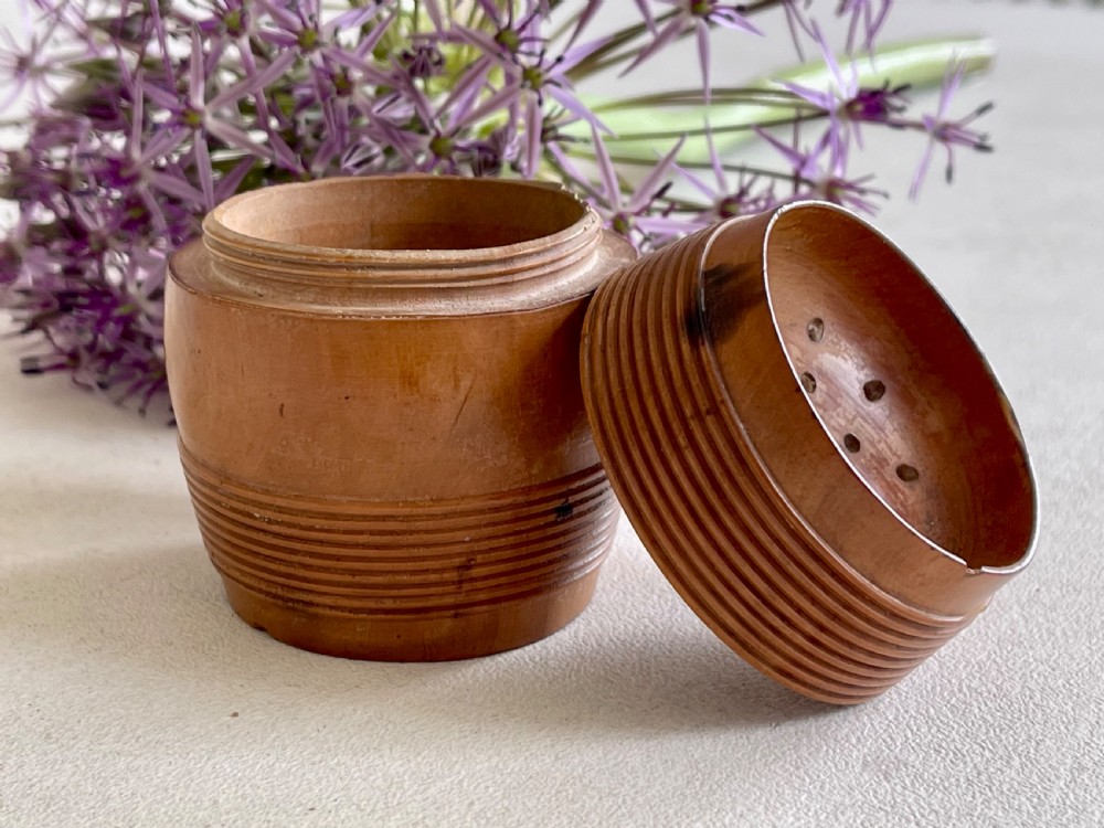 A small turned wooden pounce pot displaying a reeded base and a perforated concave top lid. View III