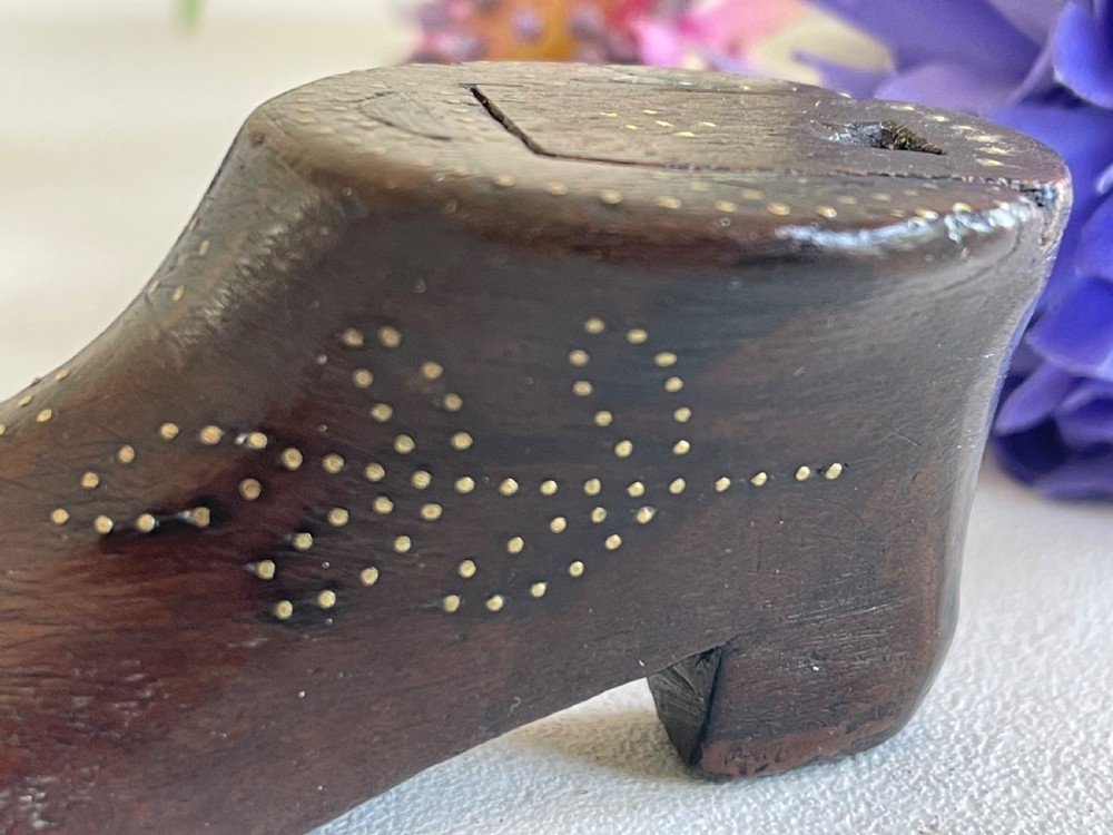 A carved dark wood snuff box fashioned in the shape of a shoe, decorated with brass pinwork floral patterns and a sliding lid on top. View II