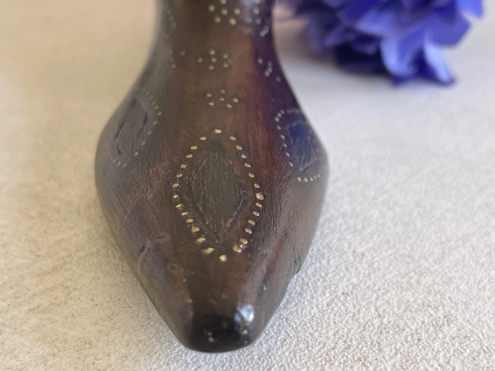 A carved dark wood snuff box fashioned in the shape of a shoe, decorated with brass pinwork floral patterns and a sliding lid on top. View VI