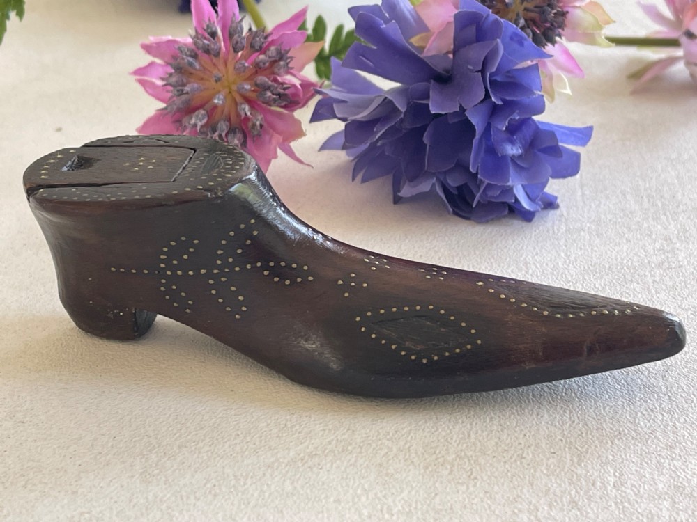 A carved dark wood snuff box fashioned in the shape of a shoe, decorated with brass pinwork floral patterns and a sliding lid on top. View VII