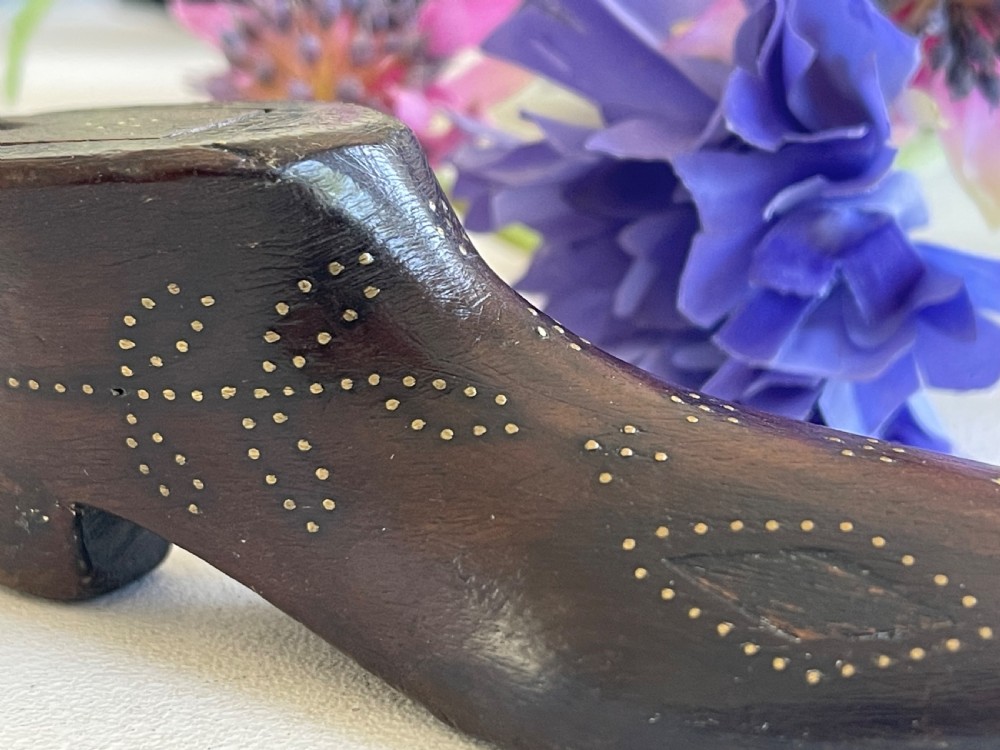 A carved dark wood snuff box fashioned in the shape of a shoe, decorated with brass pinwork floral patterns and a sliding lid on top. View VIII