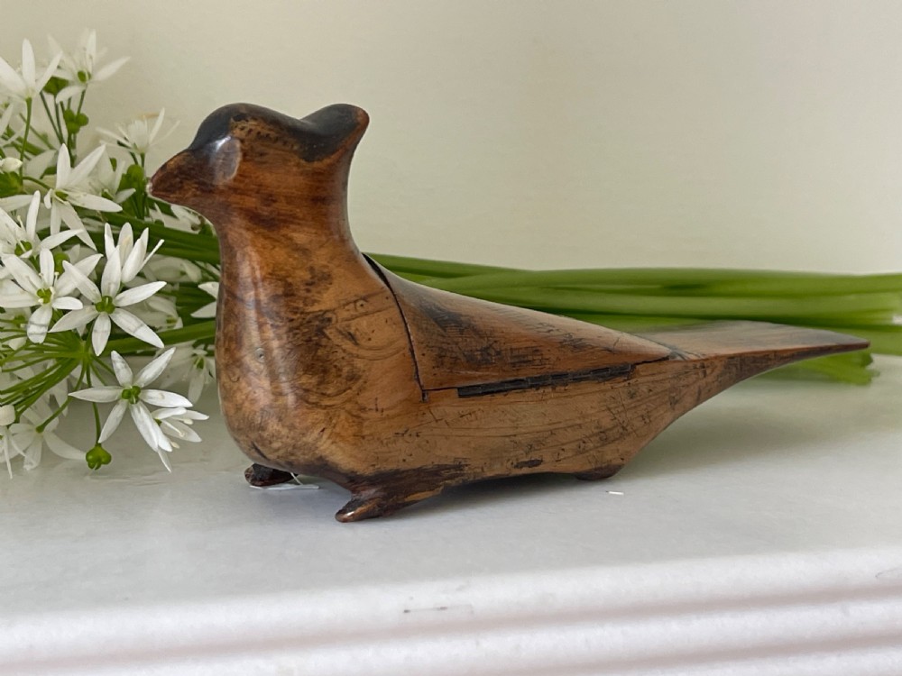 A small hand-carved wooden snuff box shaped like a bird with a polished natural timber grain and integrated hinged lid. View II