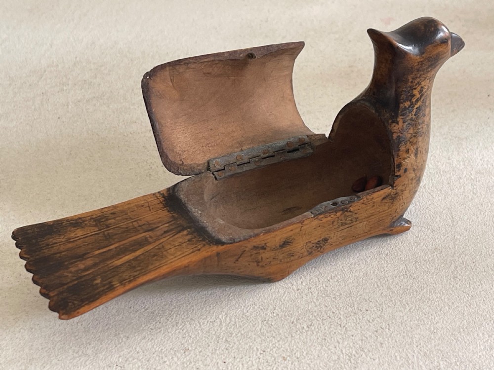 A small hand-carved wooden snuff box shaped like a bird with a polished natural timber grain and integrated hinged lid. View III