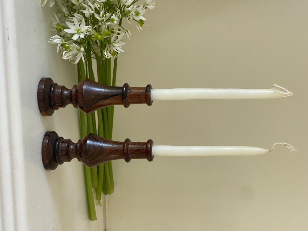 A pair of small turned dark wood taper candlesticks featuring baluster-shaped shafts and circular flat bases. View II