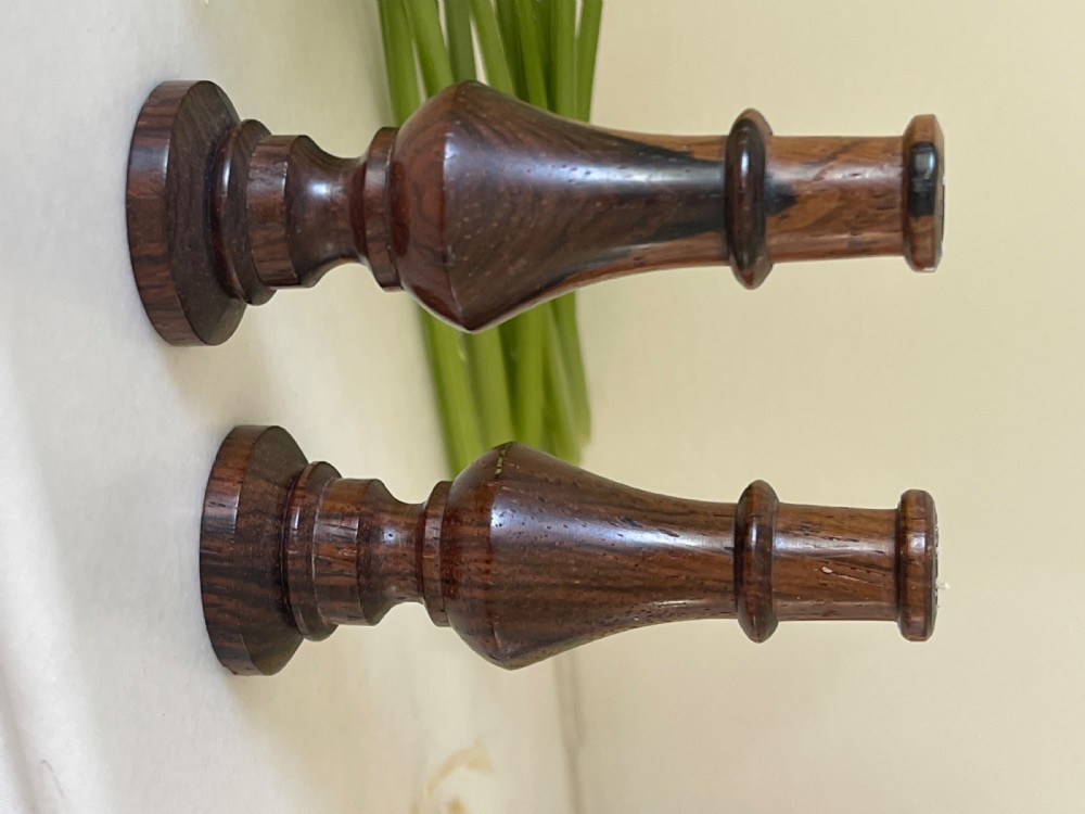 A pair of small turned dark wood taper candlesticks featuring baluster-shaped shafts and circular flat bases. View III