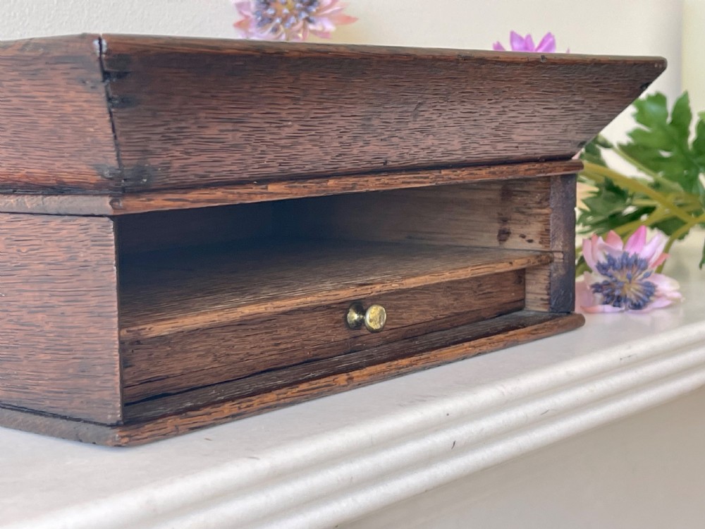 A dark oak rectangular desk tidy featuring a wide flared top tray above a single drawer fitted with a small brass knob. View V