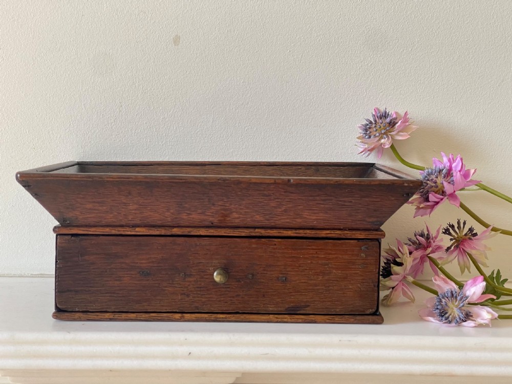 A dark oak rectangular desk tidy featuring a wide flared top tray above a single drawer fitted with a small brass knob. View VI