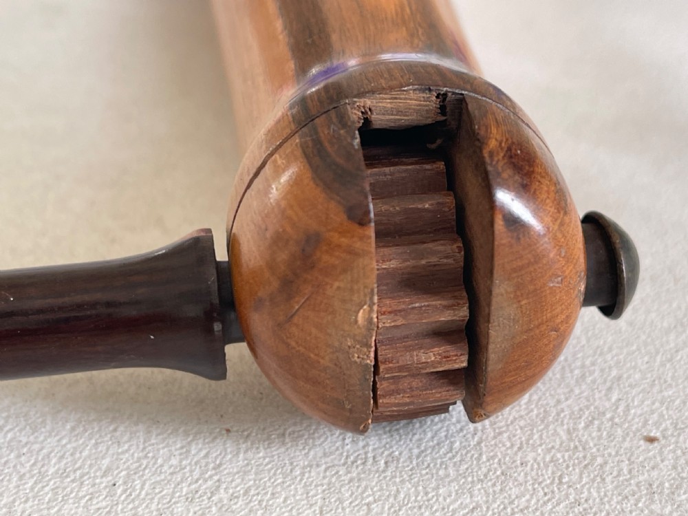 An antique turned wooden duck call with visible grain variation and linear decorative grooves. View III