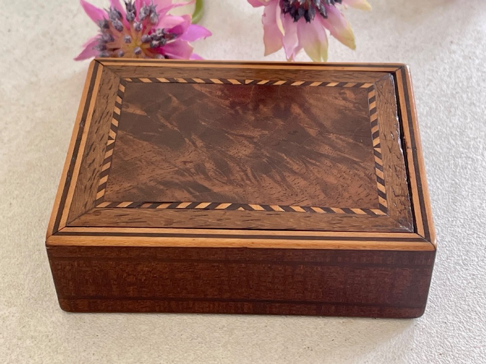 A small rectangular brown timber snuff box featuring a sliding lid with geometric chevron inlay detailing. View II