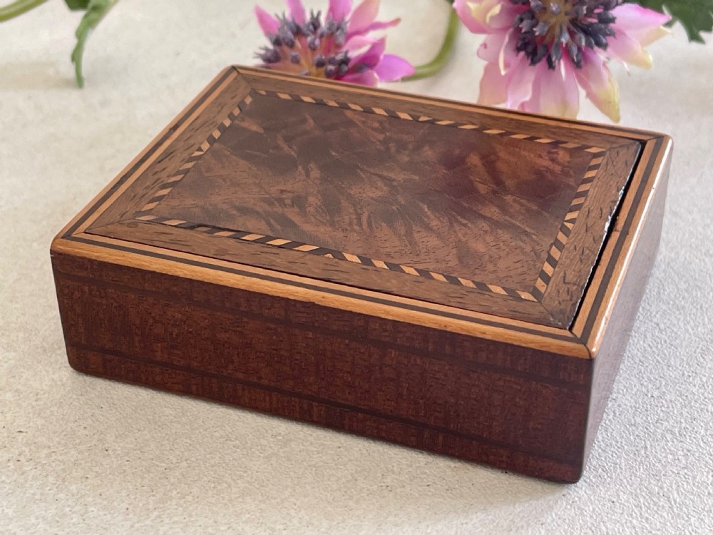 A small rectangular brown timber snuff box featuring a sliding lid with geometric chevron inlay detailing. View III