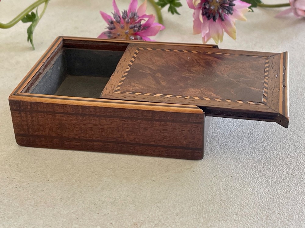A small rectangular brown timber snuff box featuring a sliding lid with geometric chevron inlay detailing. View IV