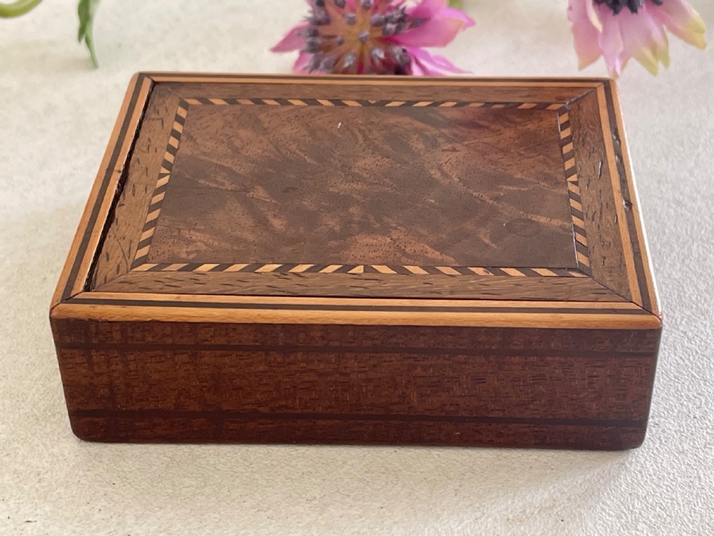 A small rectangular brown timber snuff box featuring a sliding lid with geometric chevron inlay detailing. View V
