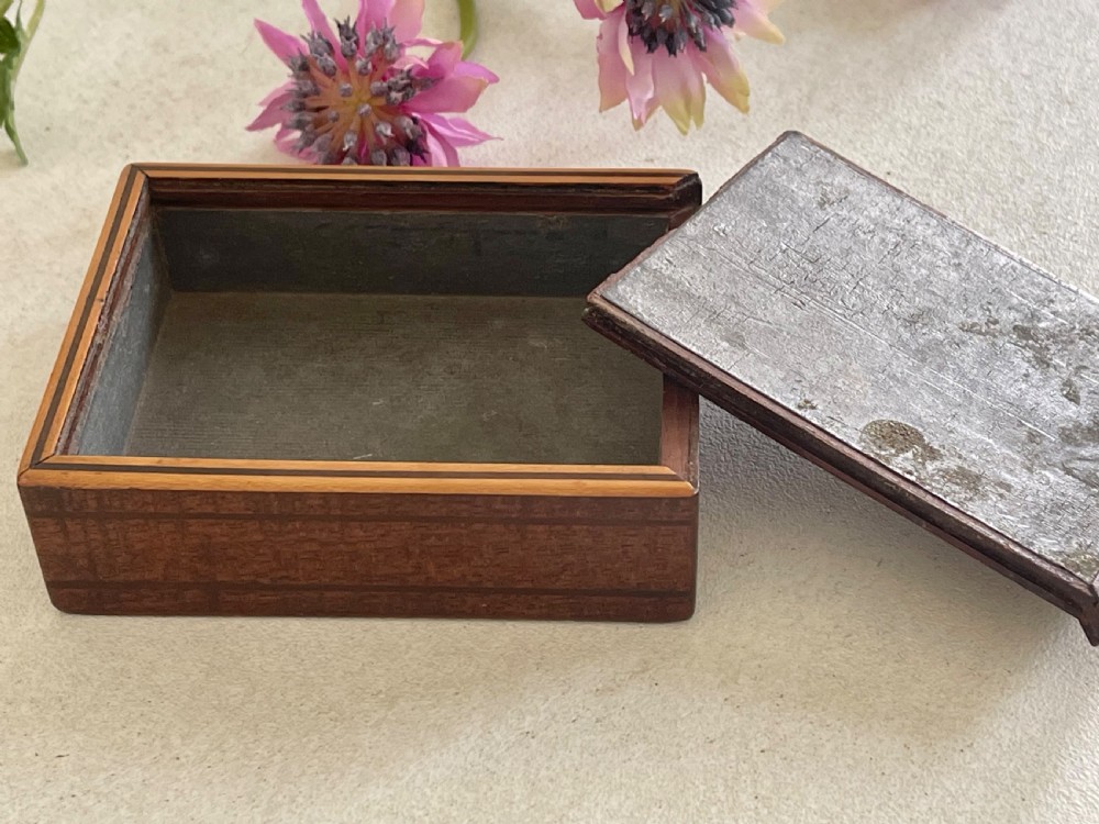 A small rectangular brown timber snuff box featuring a sliding lid with geometric chevron inlay detailing. View VII
