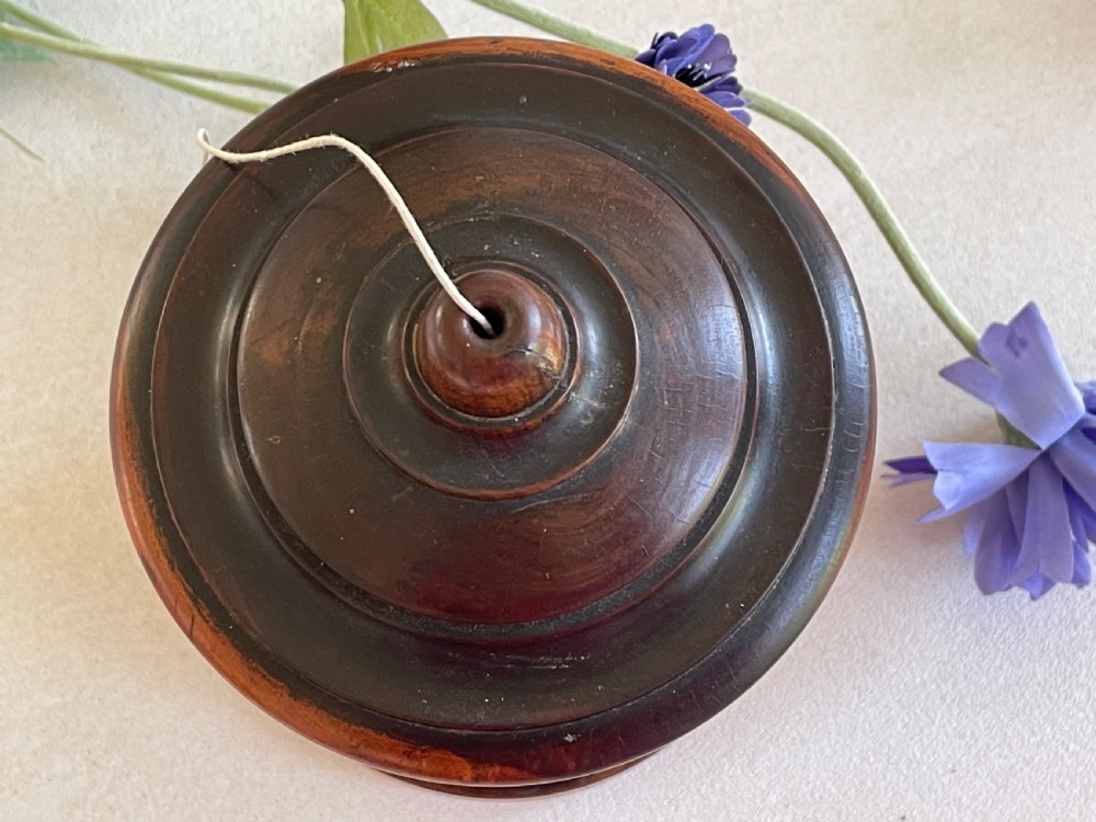 A turned dark hardwood cylindrical treen string box featuring a stepped domed lid with a central aperture for string dispenser, set on a circular stepped base. View II