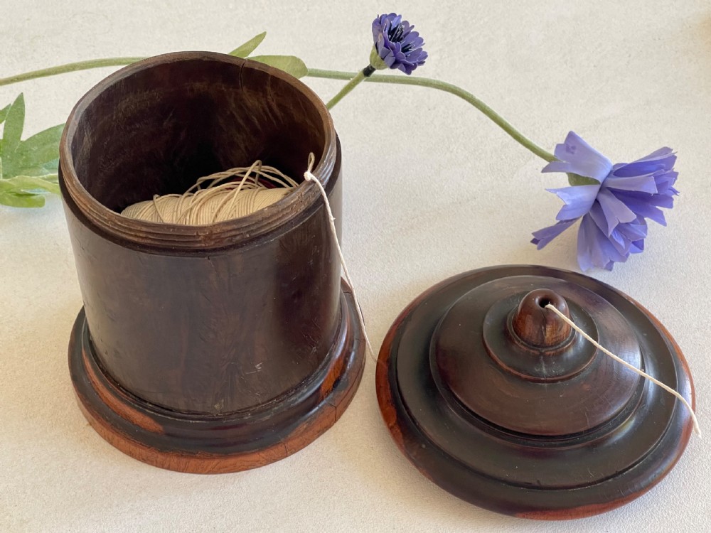 A turned dark hardwood cylindrical treen string box featuring a stepped domed lid with a central aperture for string dispenser, set on a circular stepped base. View III