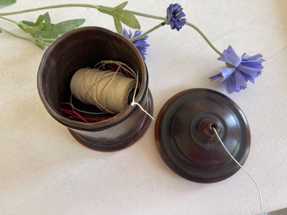 A turned dark hardwood cylindrical treen string box featuring a stepped domed lid with a central aperture for string dispenser, set on a circular stepped base. View IV