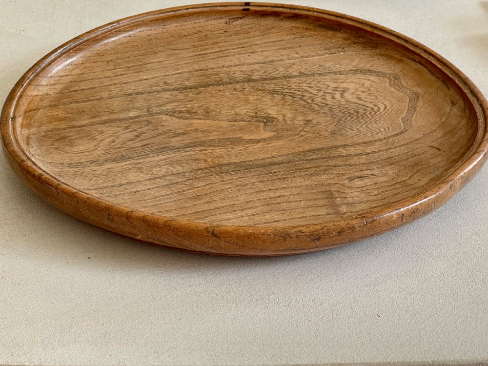 A large, shallow circular antique platter crafted from turned ash wood displaying prominent natural grain patterns. View II
