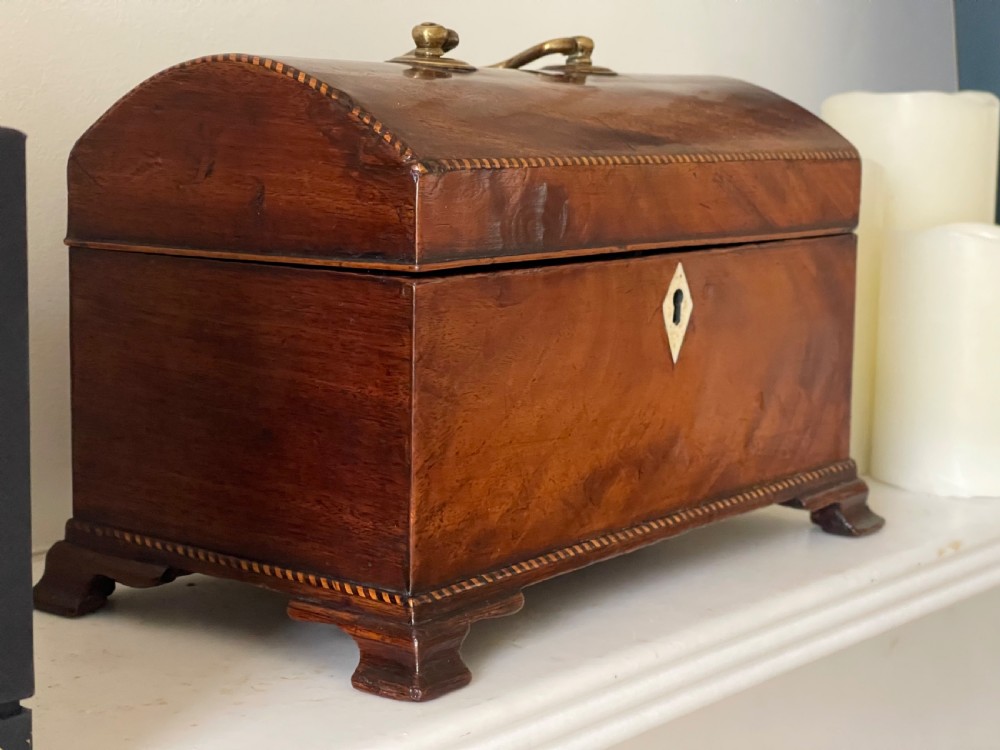 A rectangular Georgian flame mahogany tea caddy with a domed lid, brass carrying handles, and a bone keyhole escutcheon. View II
