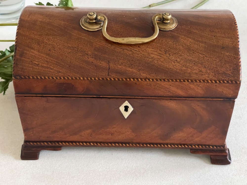 A rectangular Georgian flame mahogany tea caddy with a domed lid, brass carrying handles, and a bone keyhole escutcheon. View III