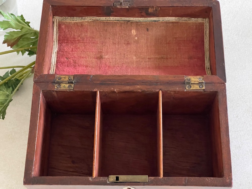 A rectangular Georgian flame mahogany tea caddy with a domed lid, brass carrying handles, and a bone keyhole escutcheon. View V