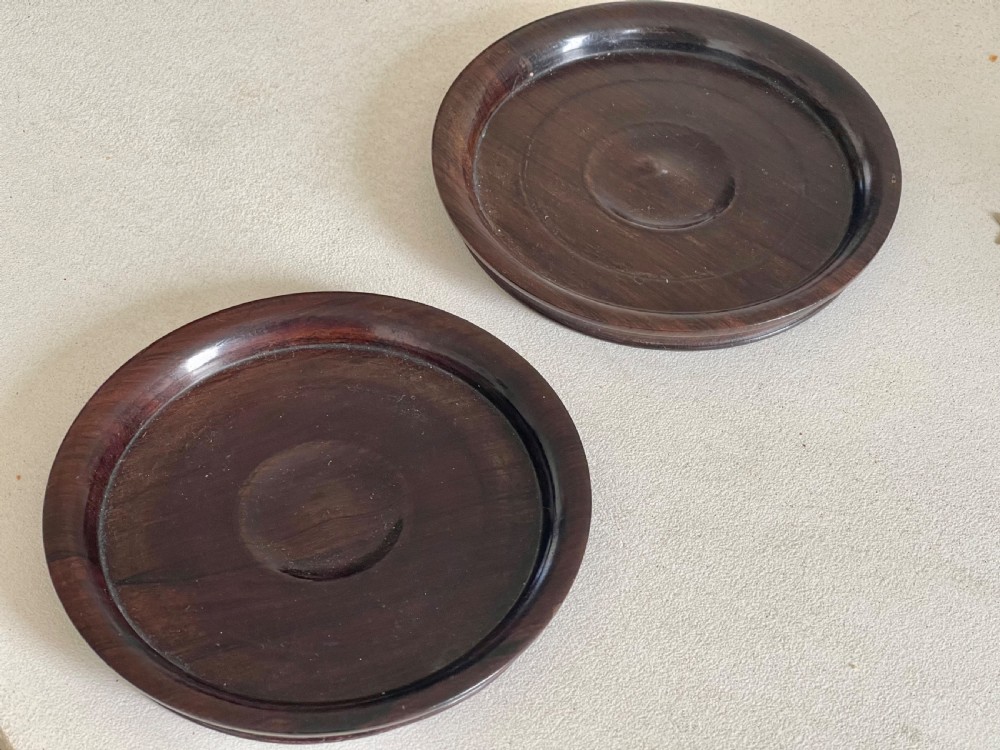 A pair of circular turned dark rosewood wine bottle coasters with raised rims and recessed centres. View III