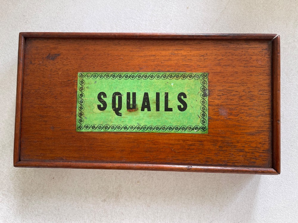 An open wooden mahogany box containing a Victorian squails game set with colourful turned wooden discs and a triangular wooden swoggle measuring tool. View II
