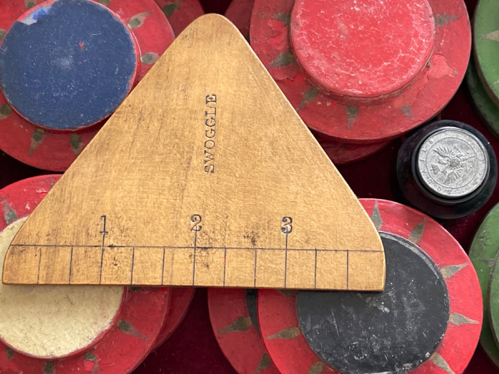 An open wooden mahogany box containing a Victorian squails game set with colourful turned wooden discs and a triangular wooden swoggle measuring tool. View III