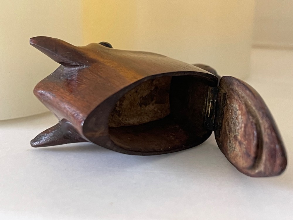 A hand-carved dark wood snuff box shaped in the detailed form of a horse head with a hinged opening at the base. View III
