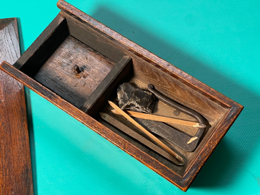 A dark carved oak tinder box with a sliding top lid and a shaped geometric end handle. View III
