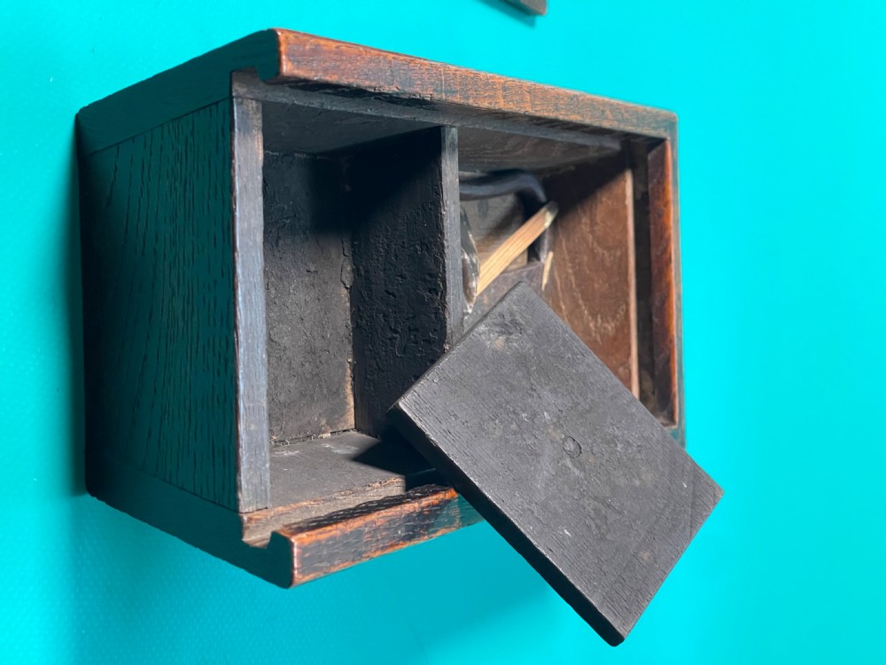 A dark carved oak tinder box with a sliding top lid and a shaped geometric end handle. View VII