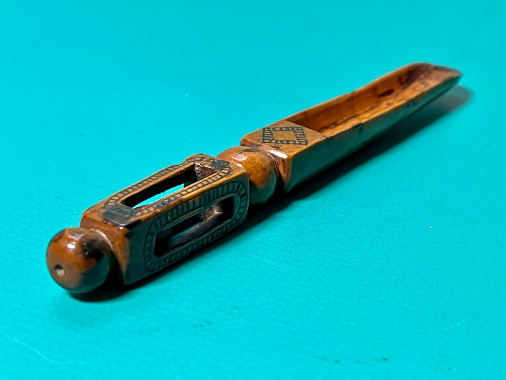 An 18th-century carved fruitwood treen apple corer with geometric incised details and a hollowed scoop.