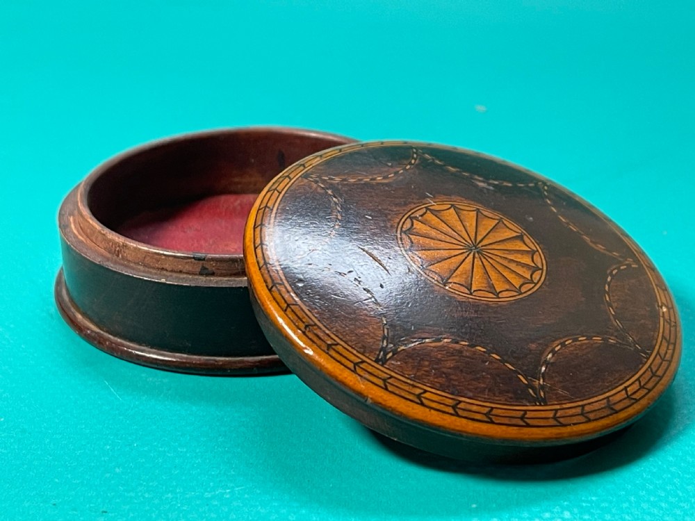 A circular Georgian wooden box featuring dark timber with light wood inlay forming a central rosette, scalloped pattern, and geometric border. View VI