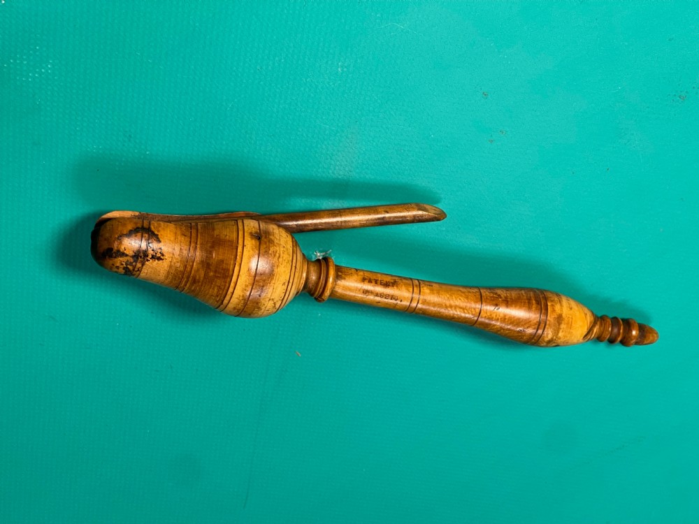 A turned boxwood teacher clicker featuring a wooden lever spring mechanism and incised line detail.