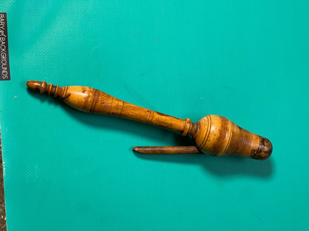 A turned boxwood teacher clicker featuring a wooden lever spring mechanism and incised line detail. View II
