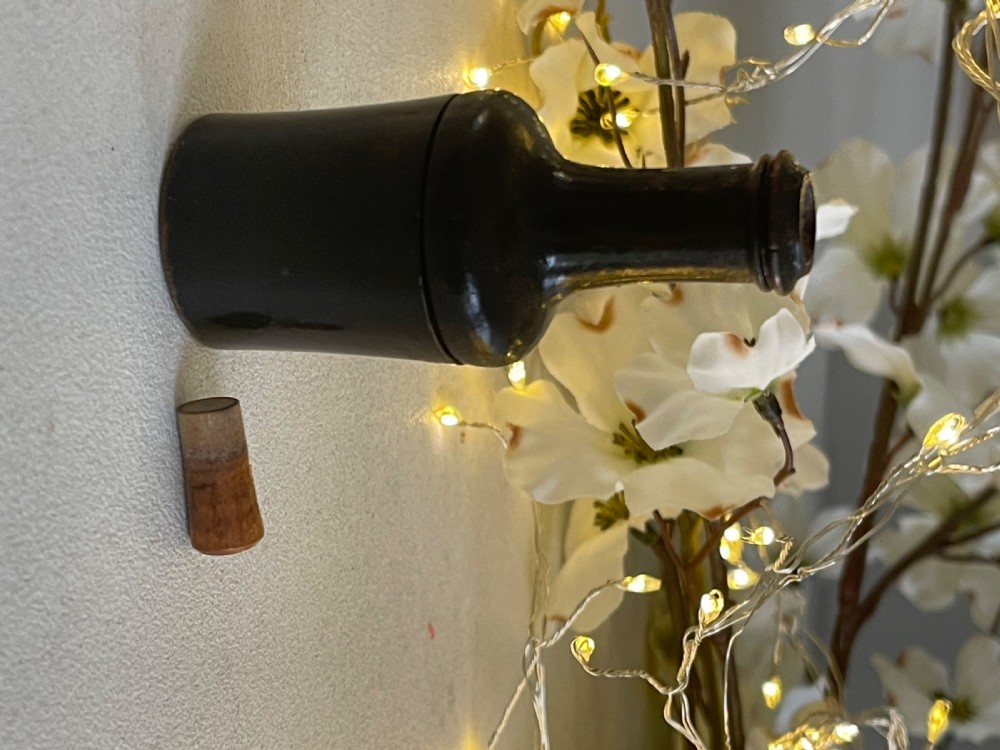 A small turned dark wood nutmeg grater shaped like a wine bottle with a wooden stopper top. View III