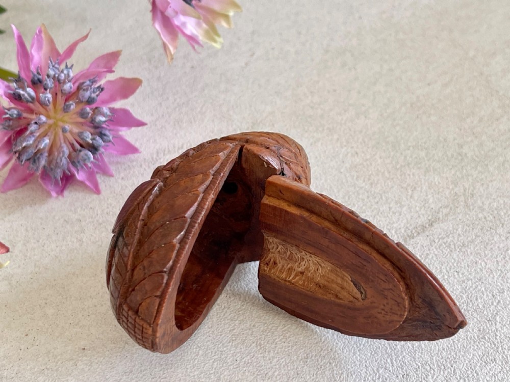 A small antique hand-carved coquilla nut snuff box shaped as a bugbear figure with detailed leaf engravings and a tiny metal hinge. View III