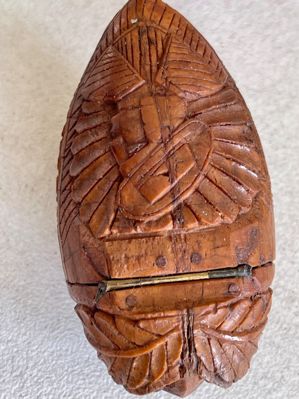 A small antique hand-carved coquilla nut snuff box shaped as a bugbear figure with detailed leaf engravings and a tiny metal hinge. View V