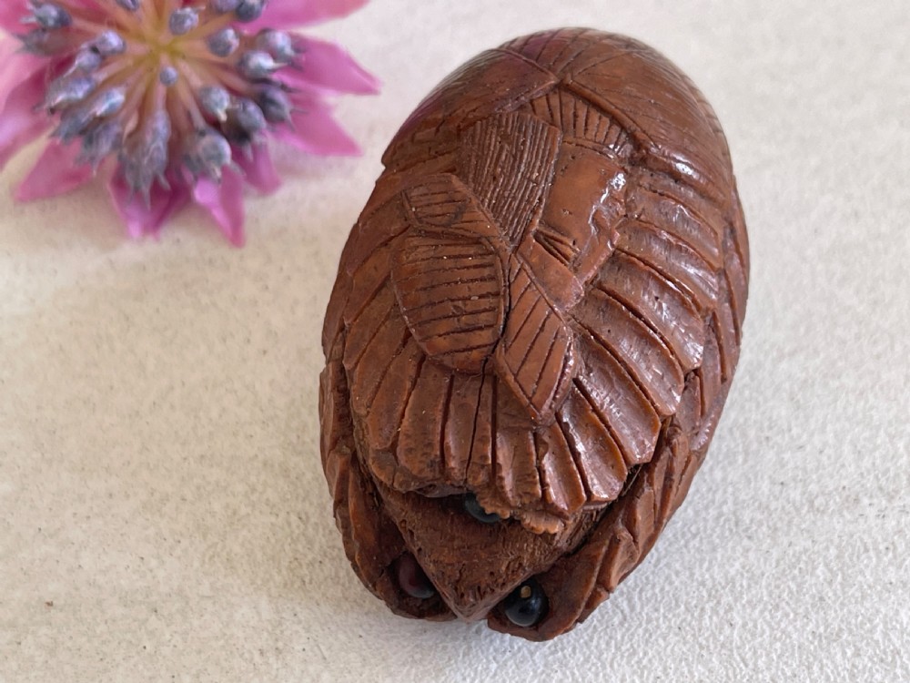 A small antique hand-carved coquilla nut snuff box shaped as a bugbear figure with detailed leaf engravings and a tiny metal hinge. View VI