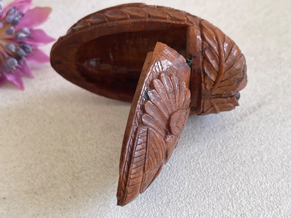A small antique hand-carved coquilla nut snuff box shaped as a bugbear figure with detailed leaf engravings and a tiny metal hinge. View VII